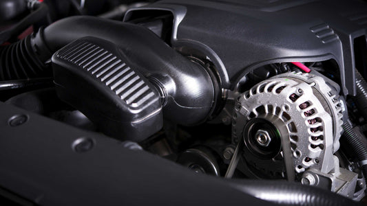 Close-up view of a car alternator and engine components under the hood.