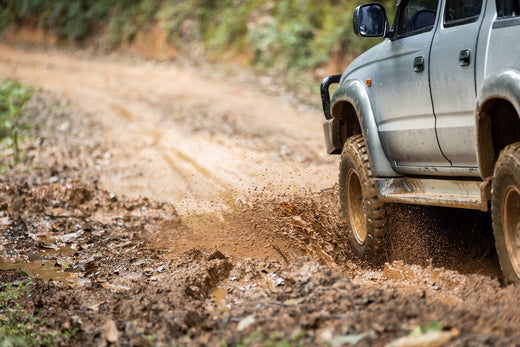 off road vehicle driving through muddy trail splashing dirt