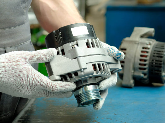 mechanic holding a car alternator with protective gloves