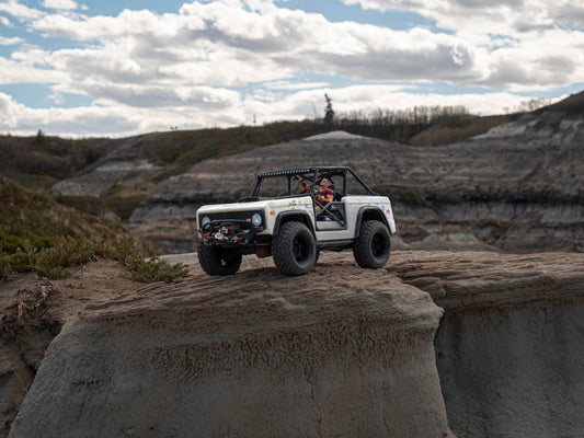 miniature jeep with man inside on rock ledge